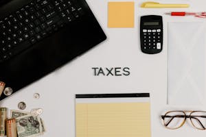 Organized office supplies for managing taxes, featuring a calculator, keyboard, and notepad.