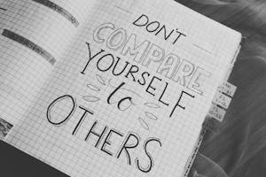 Black and white photo with motivational handwriting on a grid notebook page.