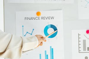 Close-up of hand pointing at finance report with charts and graphs on paper.